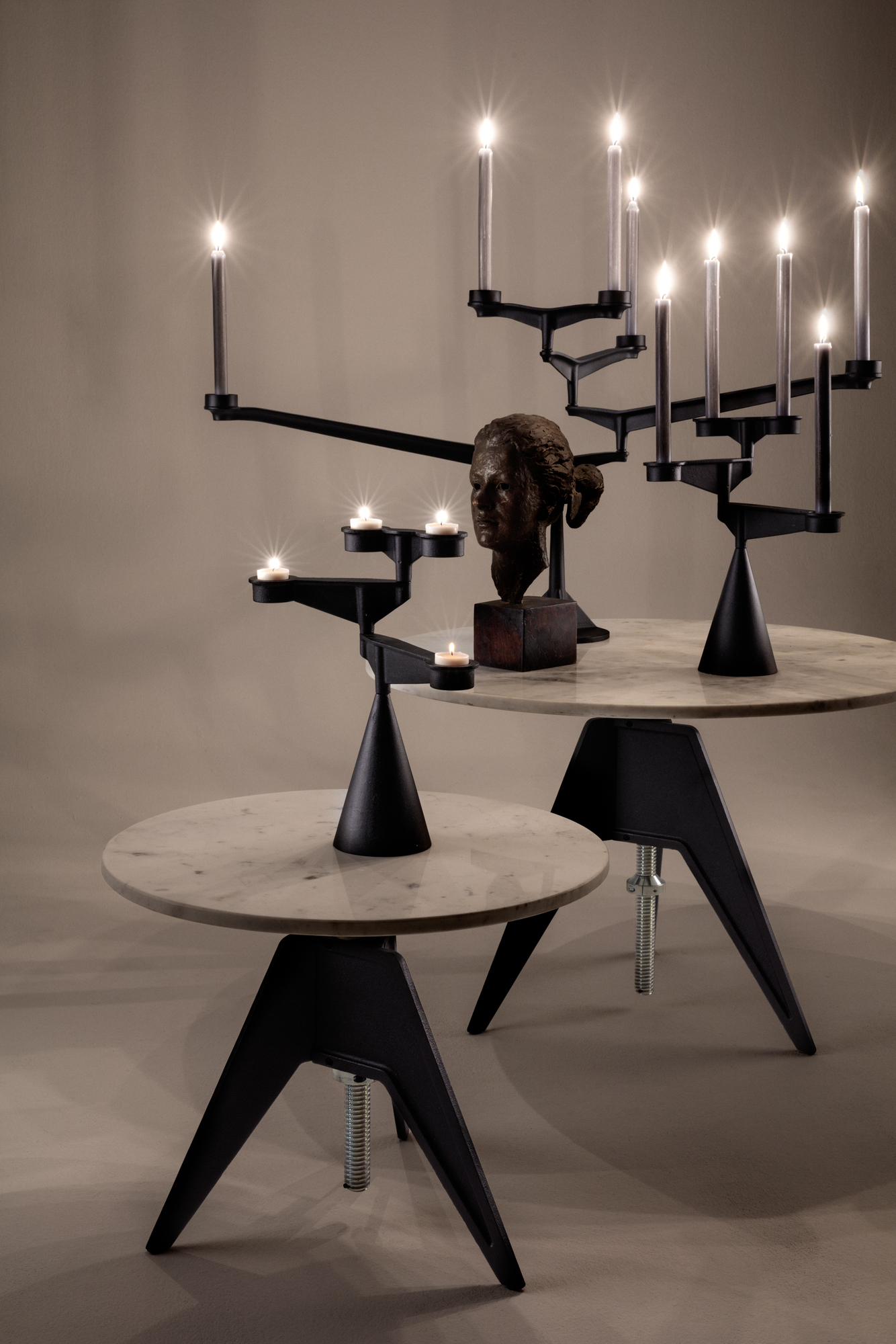 Spin Candelabra Kerzenständer von Tom Dixon: Schwarzer, moderner Leuchter mit brennenden Kerzen auf Marmortischen.
