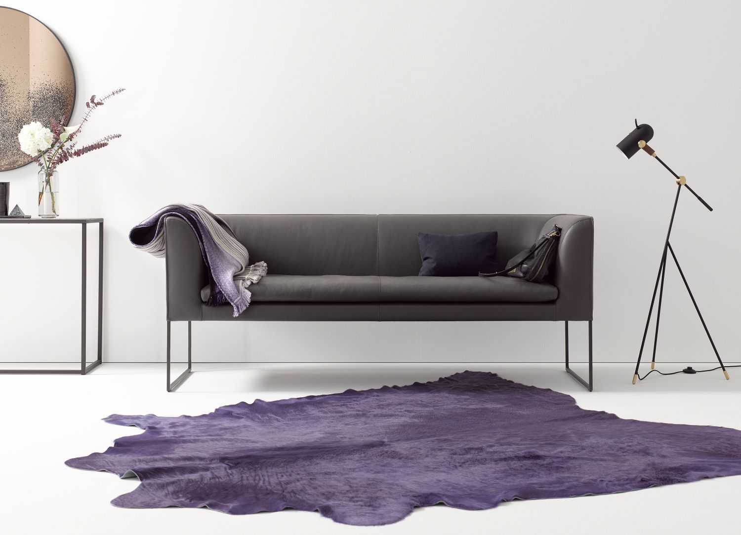 Graue Mell Polsterbank von Cor mit Kissen und Decke auf lila Teppich. Moderne Wohnzimmer Einrichtung.