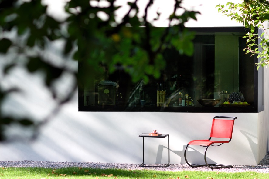 Thonet Beistelltisch Set B 9 im Außenbereich mit rotem Freischwinger Stuhl vor Fenster.