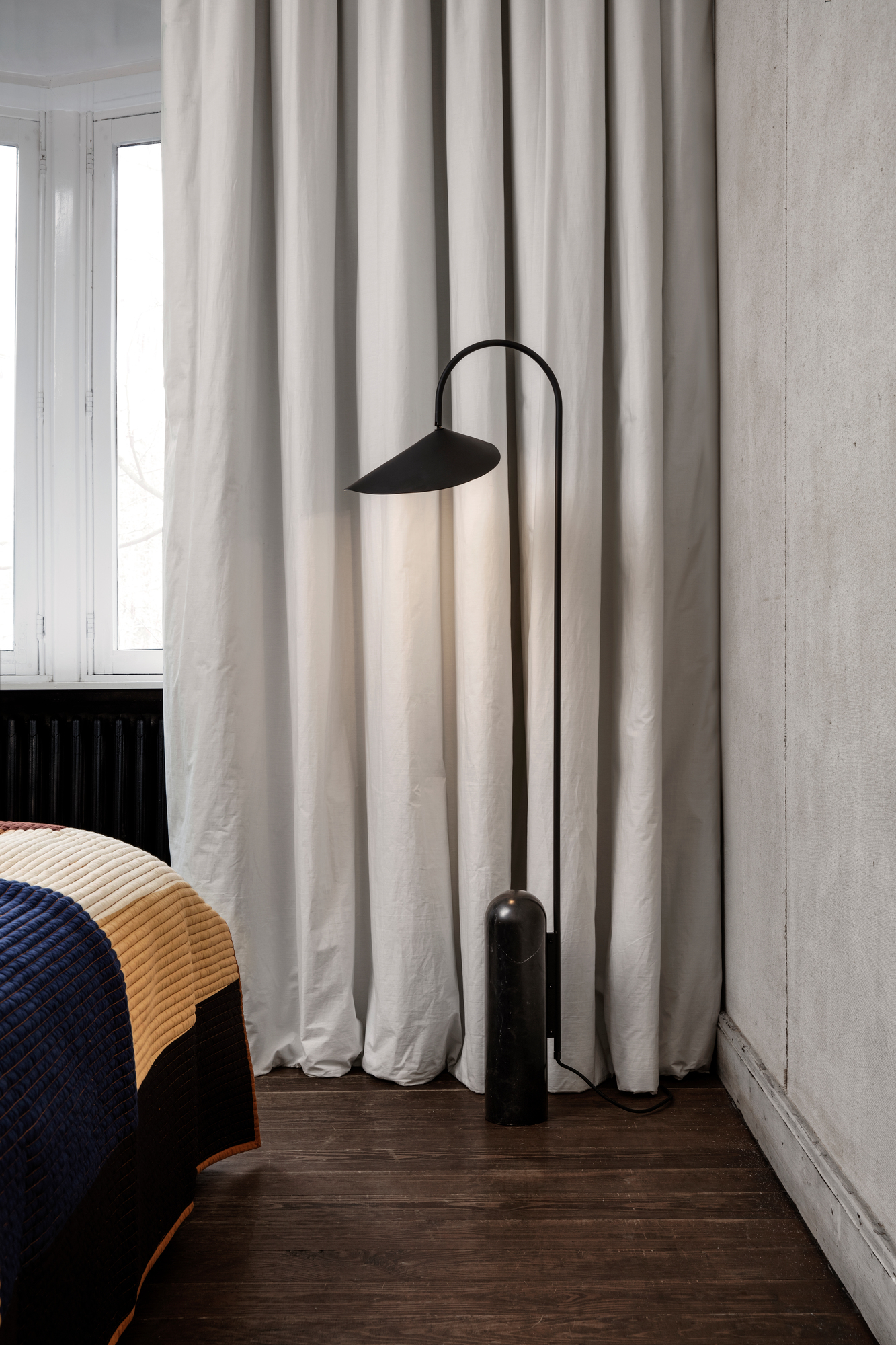 Schwarze Arum Stehlampe von Ferm Living mit schirmförmigem Lampenkopf und zylindrischem Fuß.