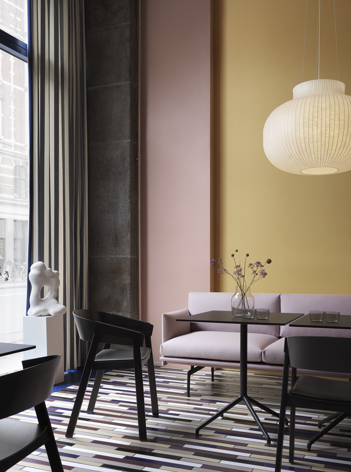 Muuto Outline Studio Sofa in Rosa, minimalistisches Design, kombiniert mit schwarzen Stühlen und Tischen.