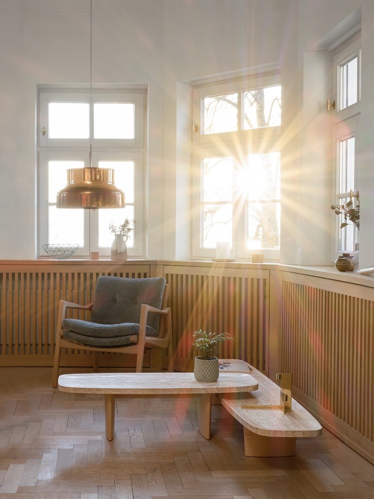 Heller Raum mit Classicon Couchtisch Matéria, Sessel und Parkettboden im modernen Design.