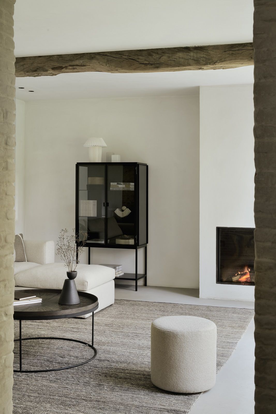 Wohnzimmer mit Ethnicraft Couchtisch, rund, aus dunklem Holz und Metallgestell. Dekorative Vase darauf.