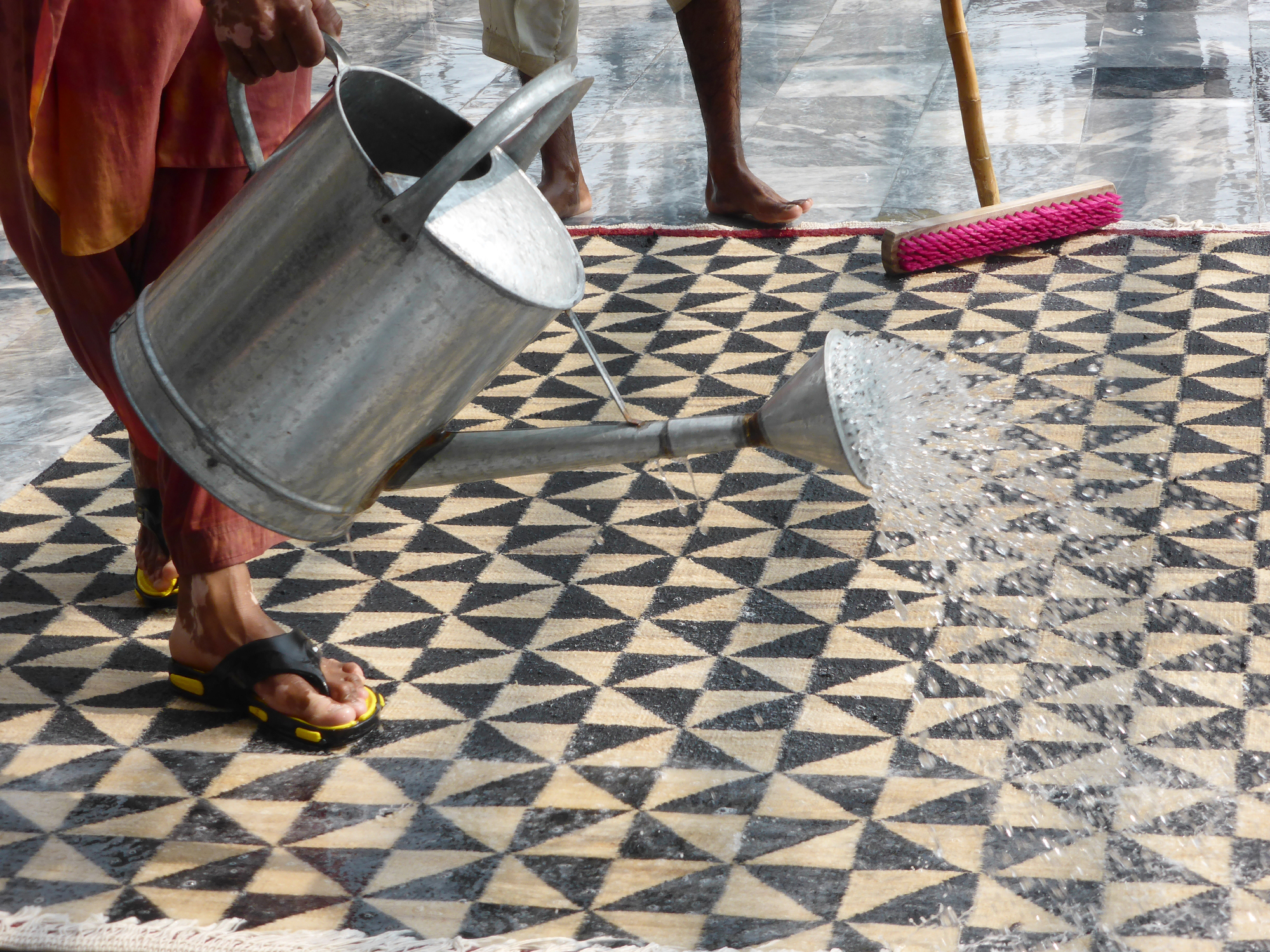 Nanimarquina Teppich mit Dreiecksmuster wird mit einer Gießkanne bewässert. Moderner Designerteppich.