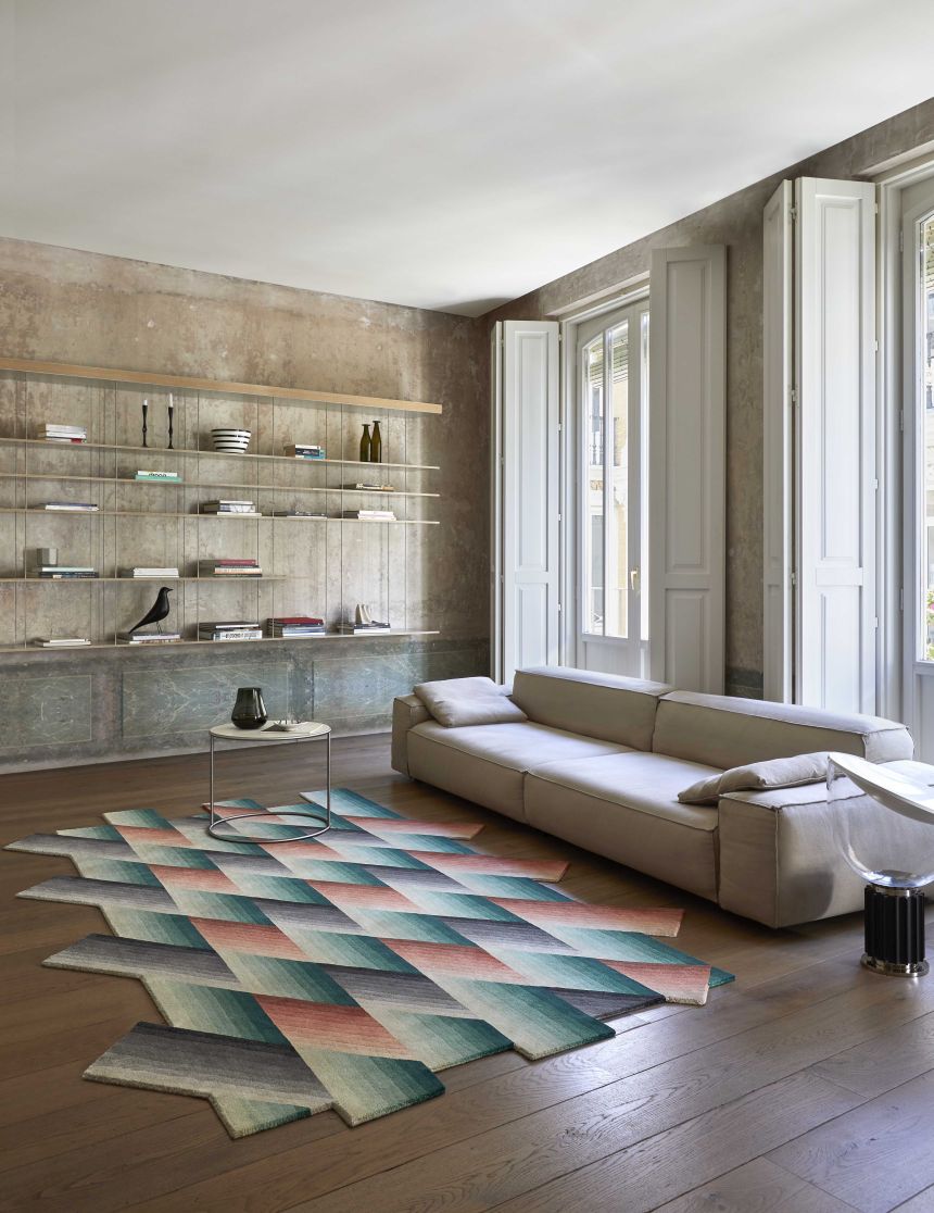 Wohnzimmer mit blauem Mirage Teppich von Gan, geometrisches Muster, Sofa und Regalen.