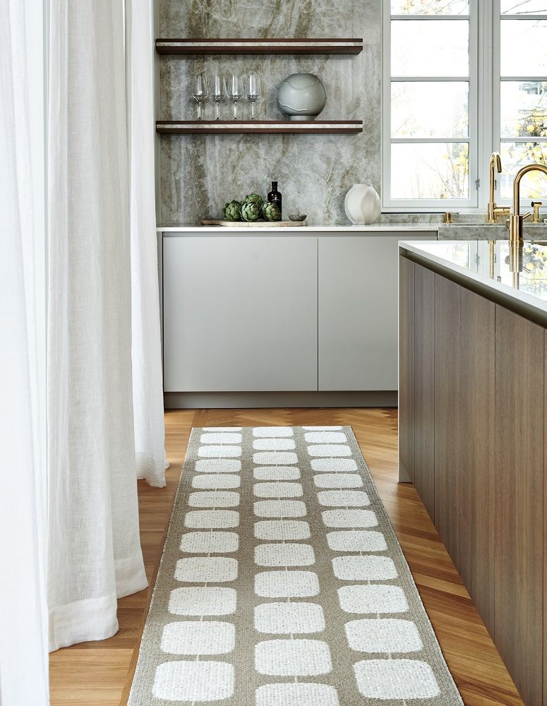 Pappelina Kunststoffteppich in Ocker/Vanille (70x200 cm) im Küchenbereich auf Holzboden. Rechteckiges Muster. Strapazierfähiger Teppich für Innenräume.