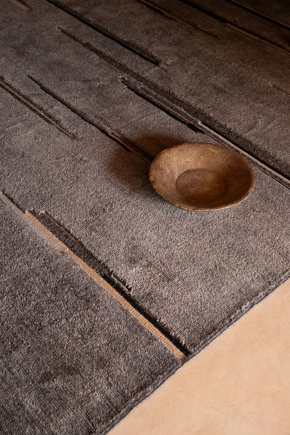 Detailaufnahme des grauen Colorado Teppichs von Nanimarquina mit natürlicher Schale. Hochwertiger Designerteppich für Wohnräume.