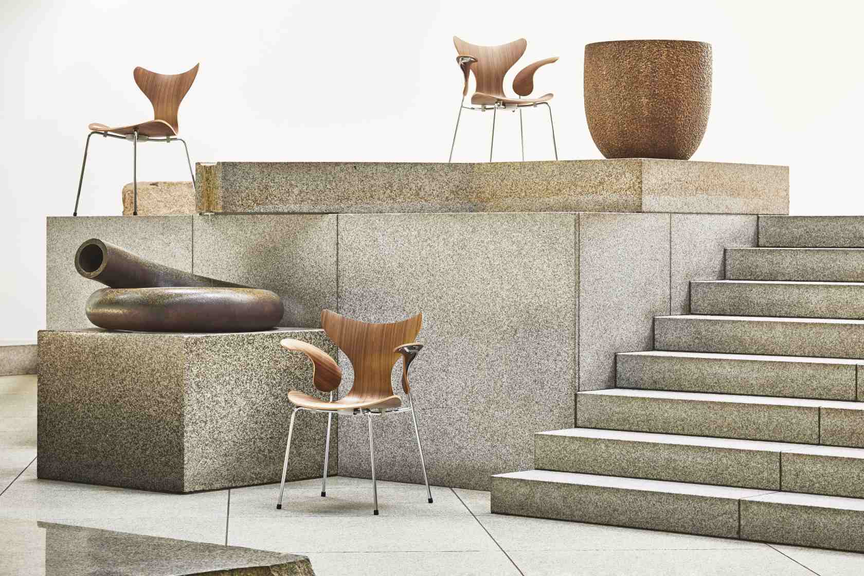 Mehrere Fritz Hansen Lily Stühle 3108 aus Holz und Stahl auf Steinstufen. Designklassiker.