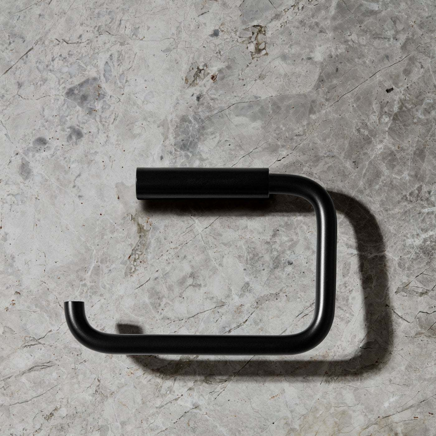 Schwarzer Modo WC-Rollenhalter von Blomus auf grauem Marmor-Hintergrund. Moderner Toilettenpapierhalter für stilvolle Badezimmer.