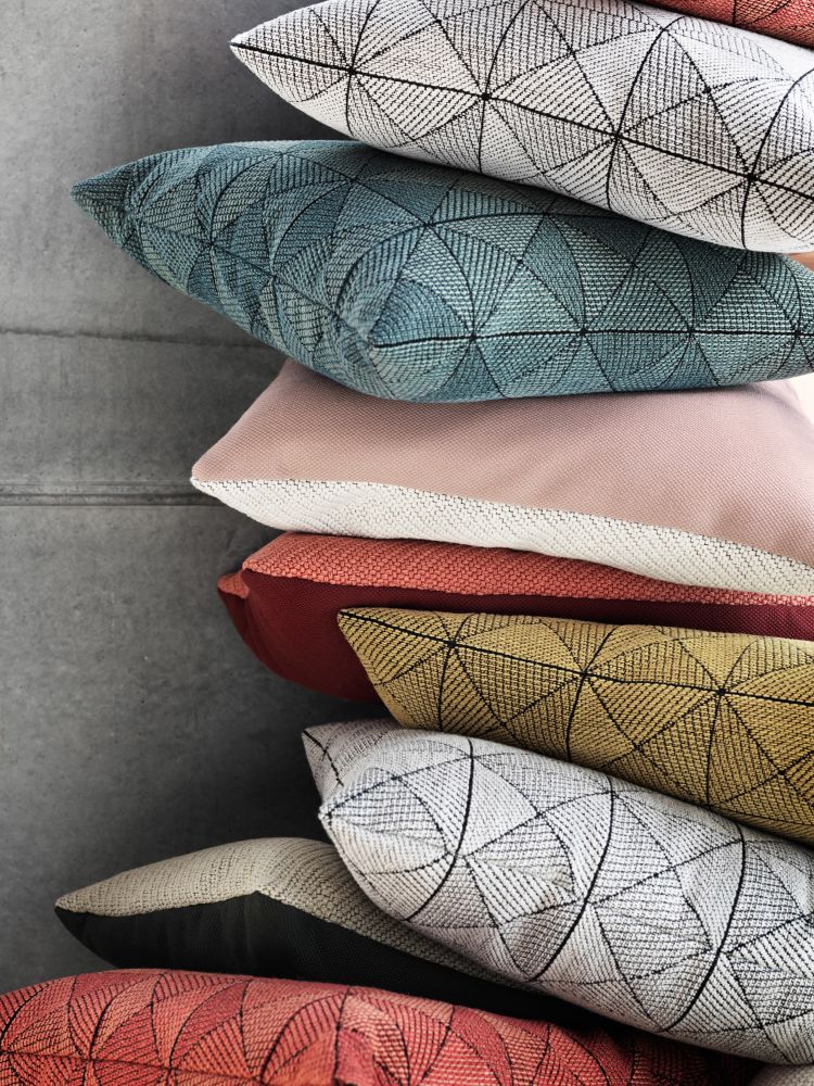 Stapel verschiedenfarbiger Muuto Tile Cushion Kissen 45x45 cm mit geometrischen Mustern für Wohnzimmer und Schlafzimmer.