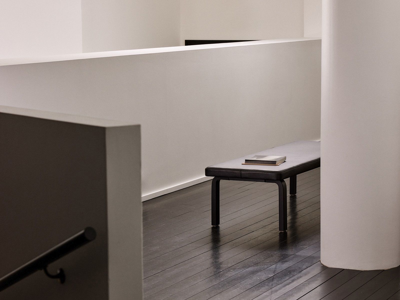 Artek Bank 167: Moderne Holzbank mit schwarzem Gestell und grauem Sitzkissen. Design Sitzbank.