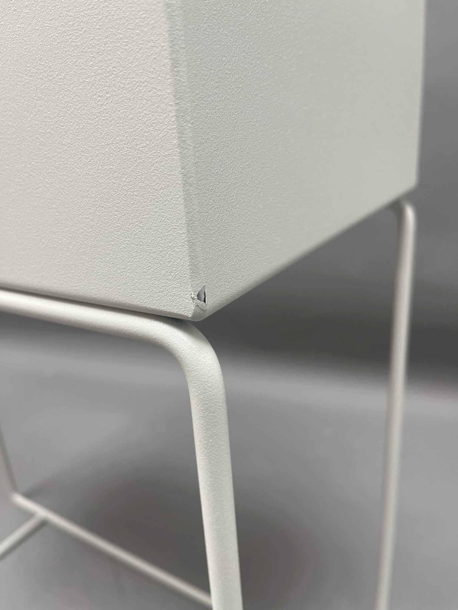 Detailaufnahme: Hellgraue Plant Box mit kleinem Defekt an der Ecke, Metallgestell. Mängelexemplar.
