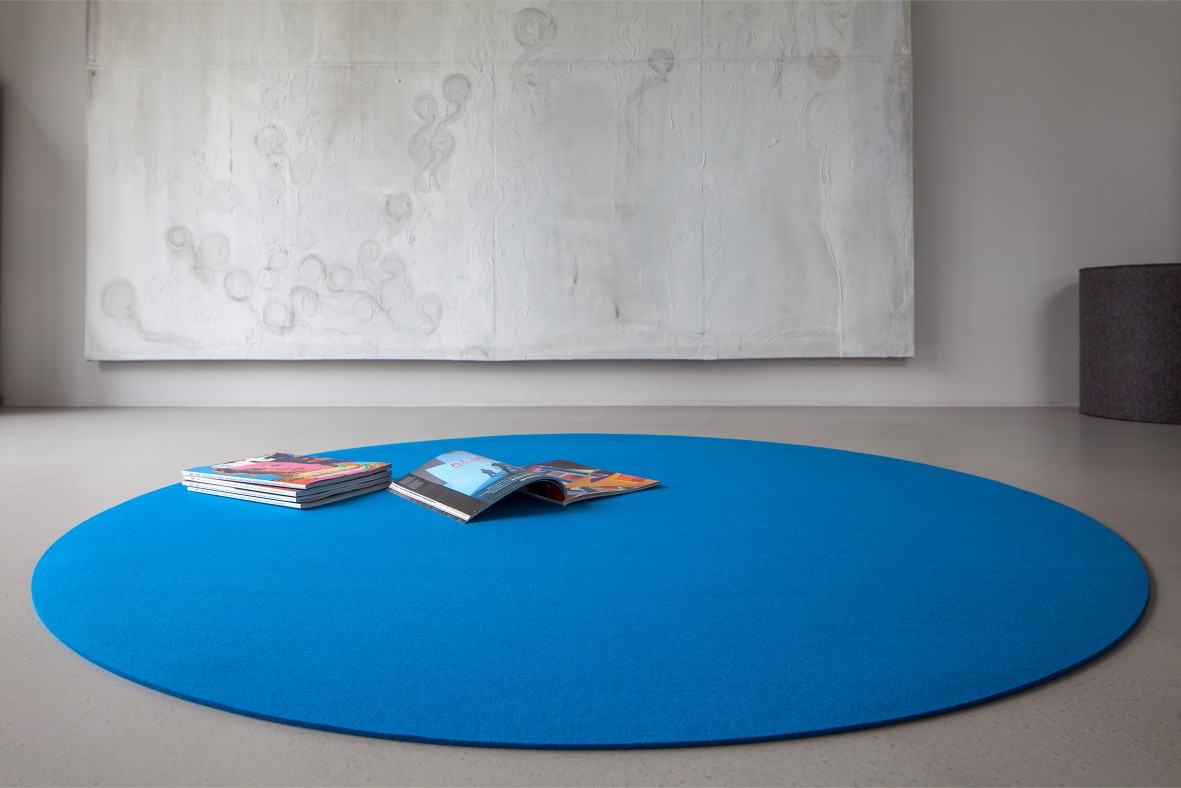 Blauer, runder Teppich Bigdot von Hey Sign im minimalistischen Wohnzimmer mit Magazinen.