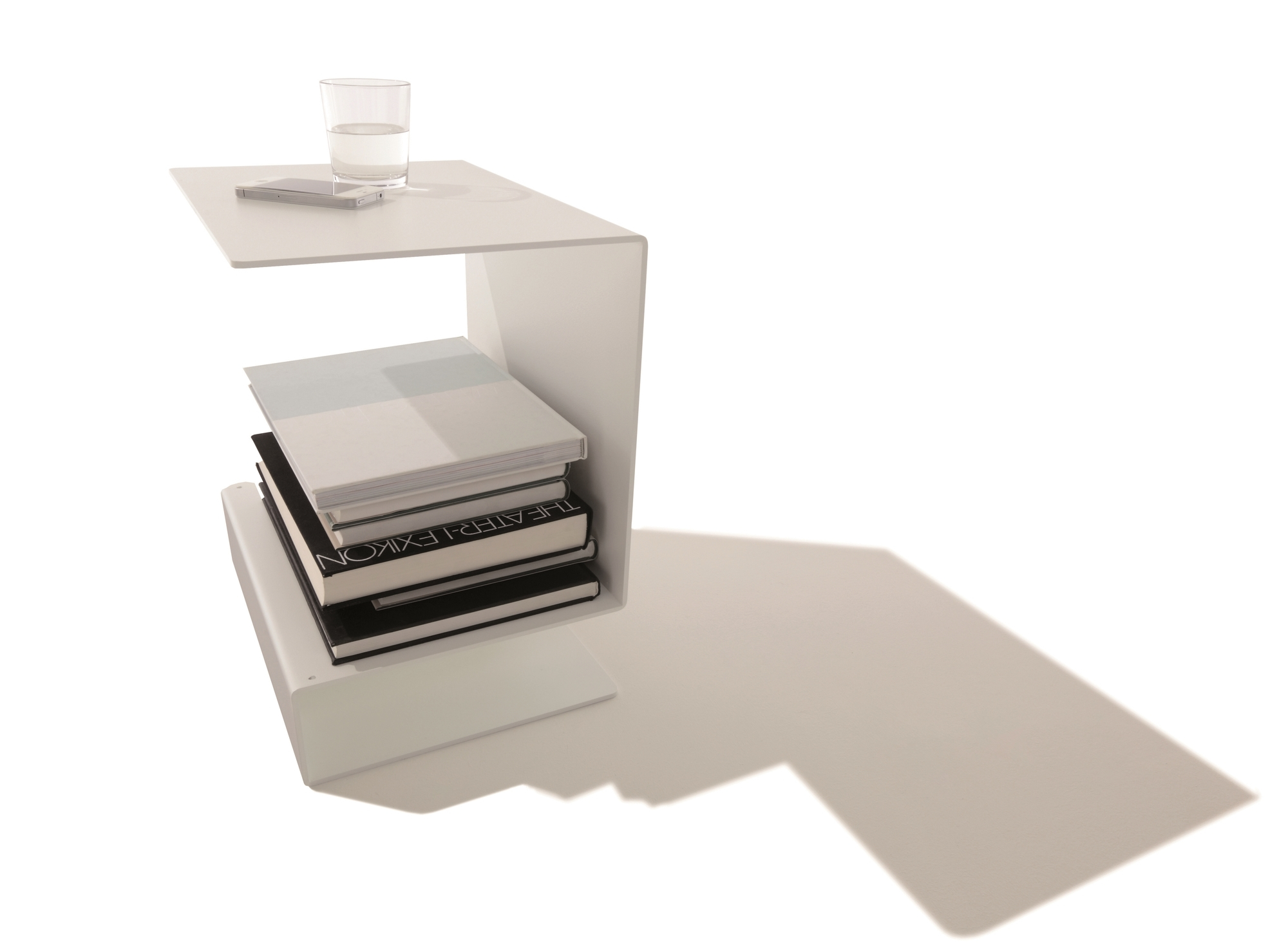 Weißer Huk Beistelltisch von Müller Möbelwerkstätten mit Büchern, Glas Wasser und Smartphone.