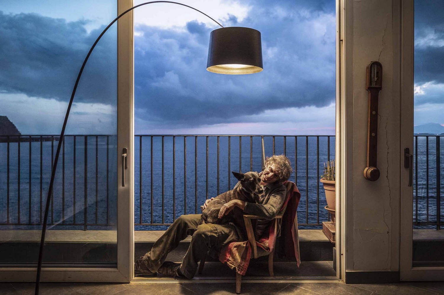 Twiggy LED Stehleuchte von Foscarini in Schwarz beleuchtet Mann mit Hund auf Balkon.