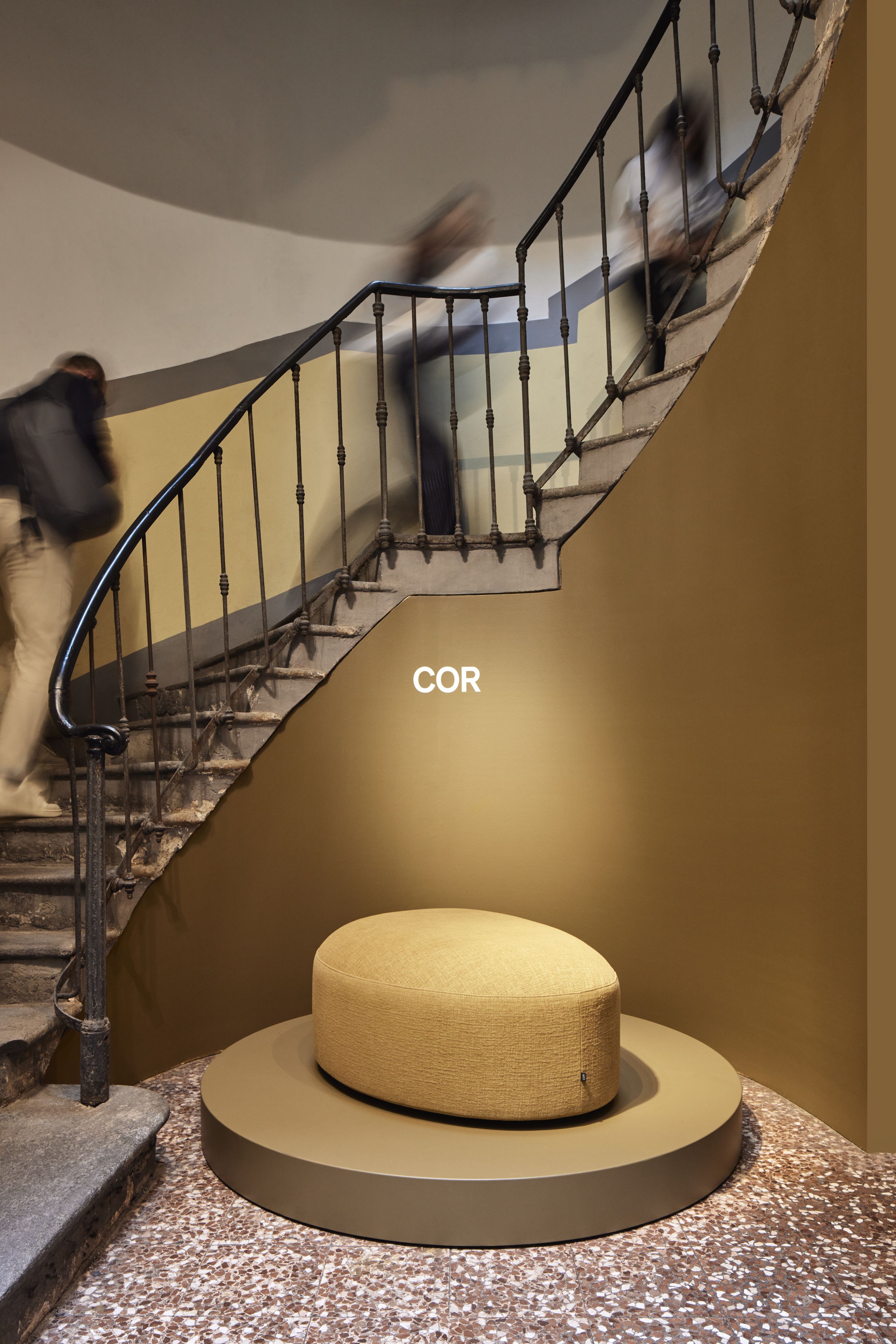 Beiger Siwa Hocker von Cor auf einer runden Plattform vor einer Treppe.