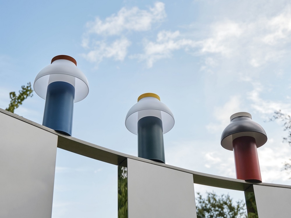 Drei PC Portable Akkuleuchten von Hay in verschiedenen Farben auf einer Mauer.