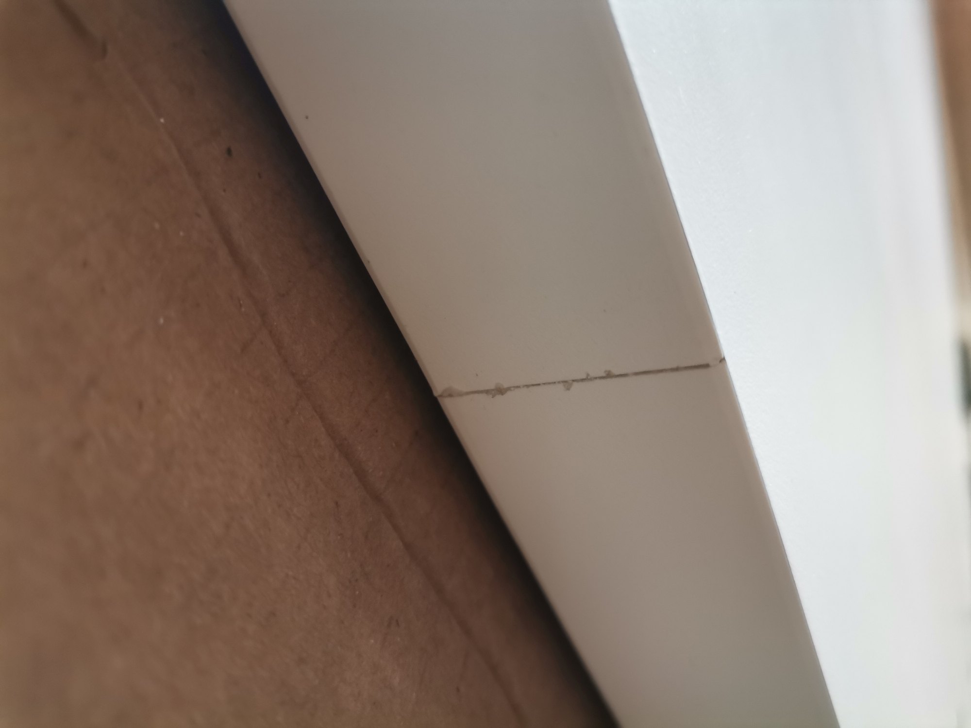 Detailaufnahme des Max Tisches in Zinkweiß: Beschädigung/Riss an der Tischkante, Mängelexemplar.