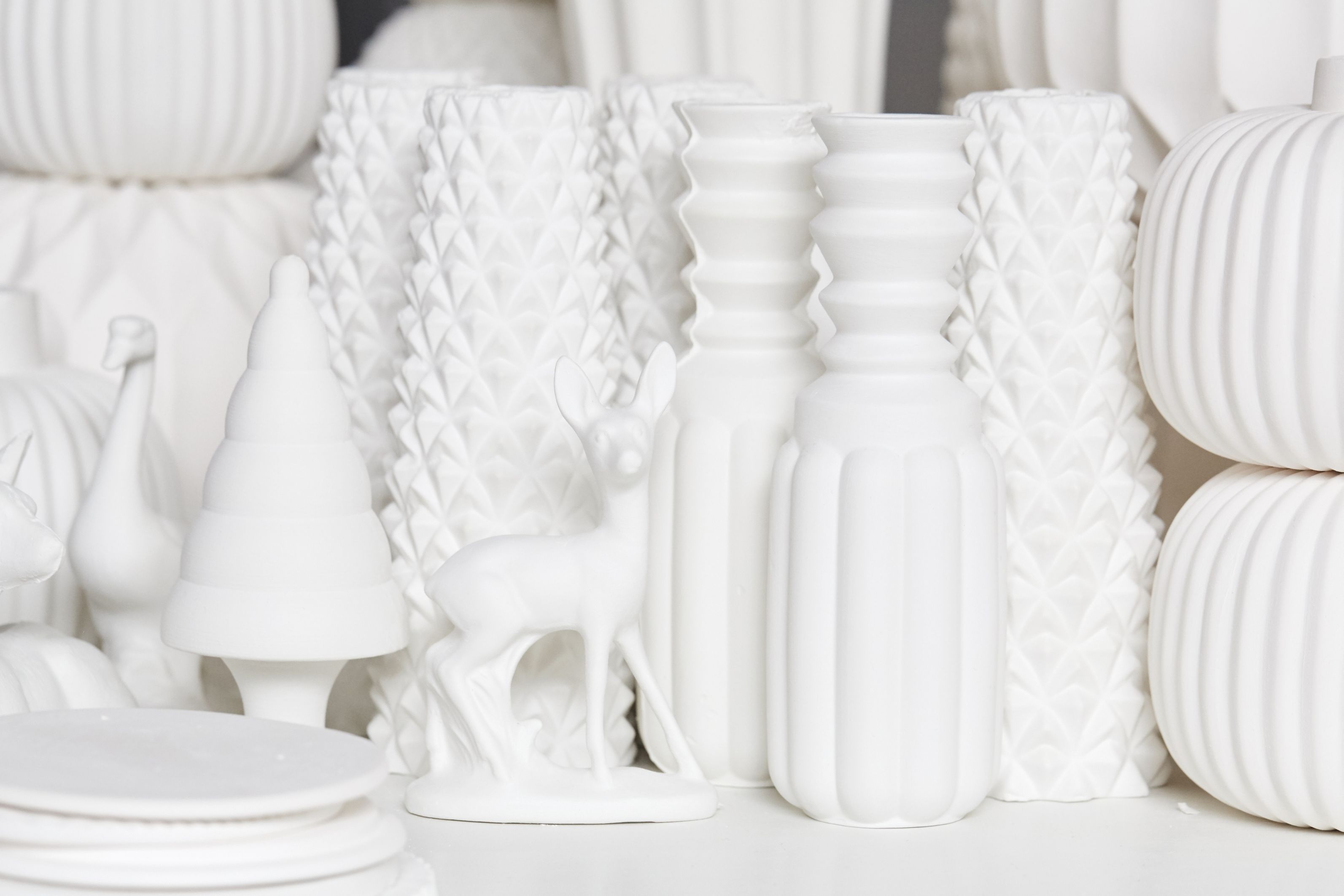 Winterliche Deko: Weißes Rehkitz als Teelichthalter von Dottir, umgeben von Vasen und Weihnachtsbaum-Figur.