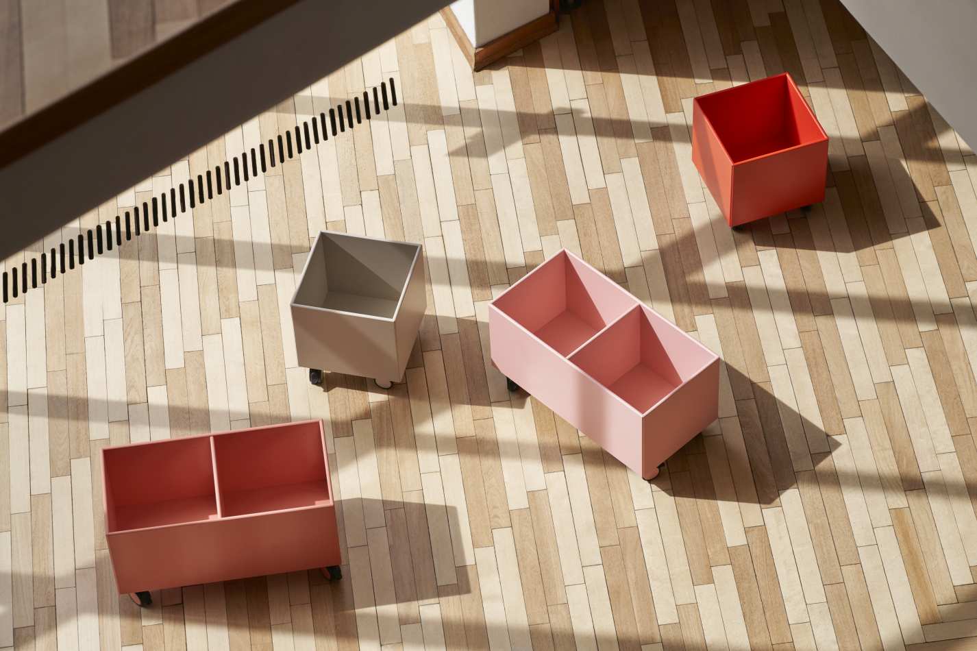 Mehrere Colour Box Aufbewahrungsboxen auf Rollen in verschiedenen Farben auf einem Holzboden.