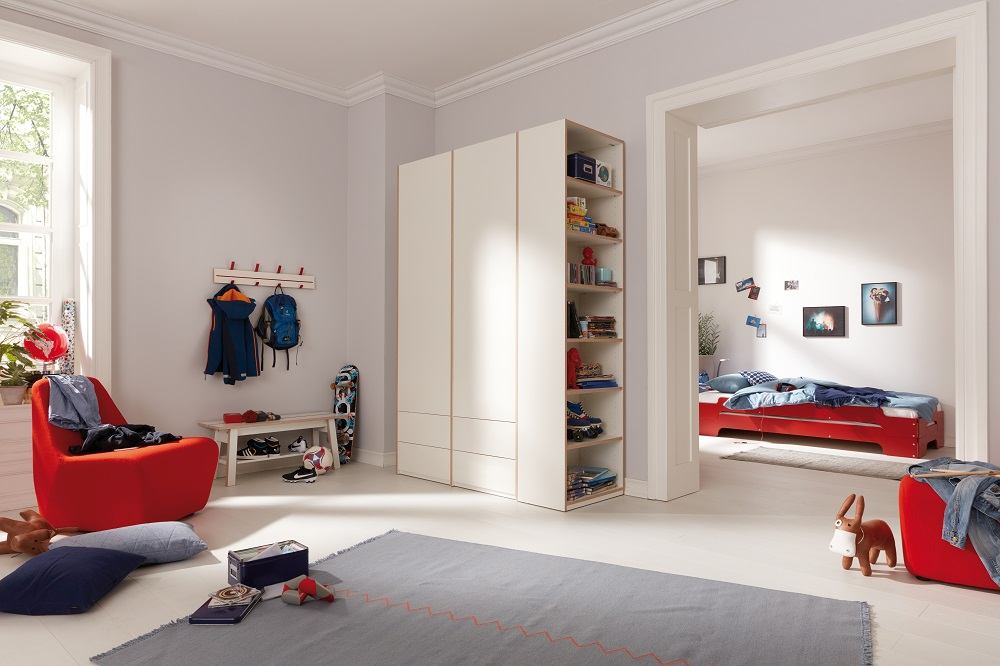 Kinderzimmer mit Müller Möbelwerkstätten Regal, Kleiderschrank und offenem Stirnelement für Spielzeug und Bücher.