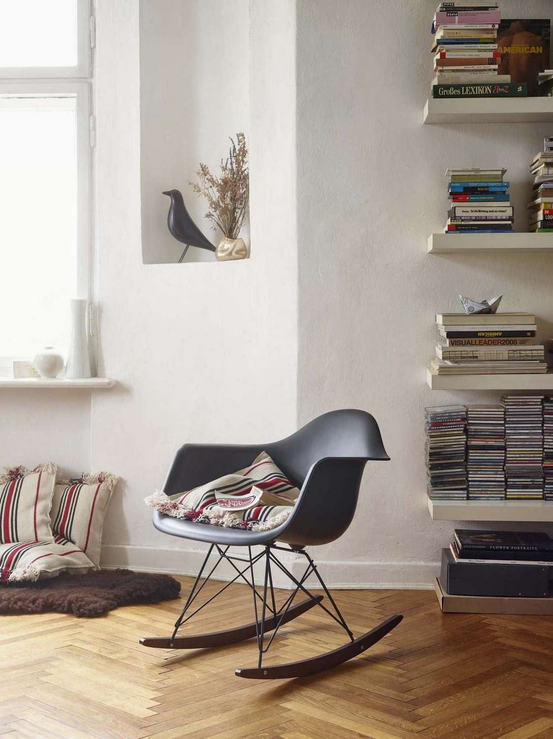 Schwarzer Eames Plastic Arm Rocking Chair RAR von Vitra mit Kissen auf Parkettboden. Design Schaukelstuhl.