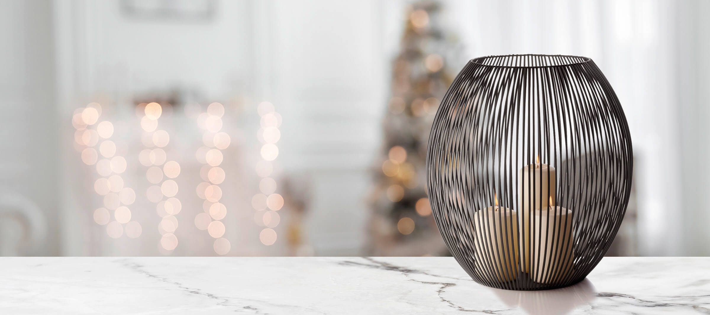 Louisiana Windlicht Philippi XXL aus schwarzem Metalldraht mit brennenden Kerzen auf Marmortisch.