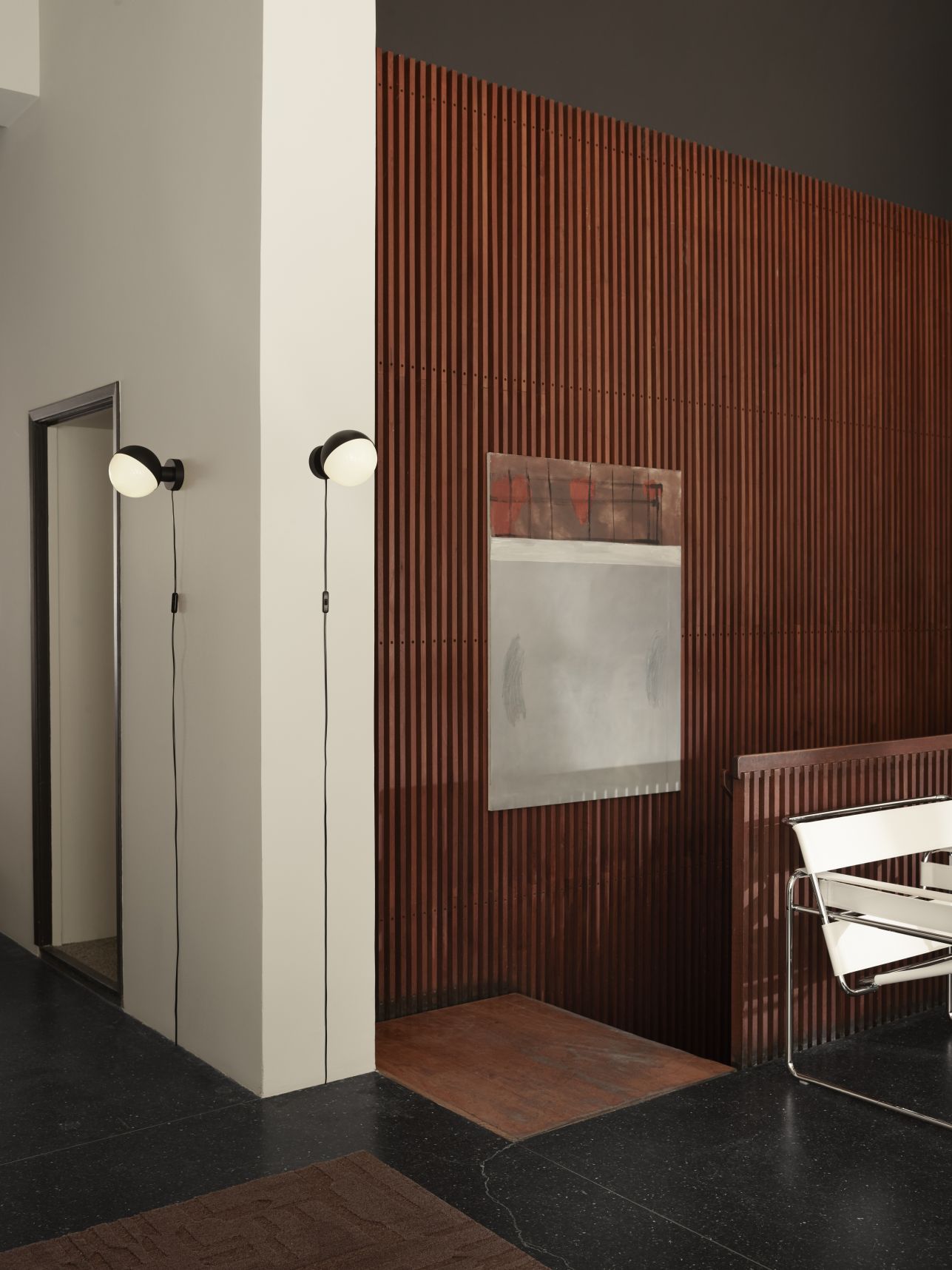 Zwei VL Studio Wandleuchten von Louis Poulsen an einer weißen Wand mit Holzwand im Hintergrund.