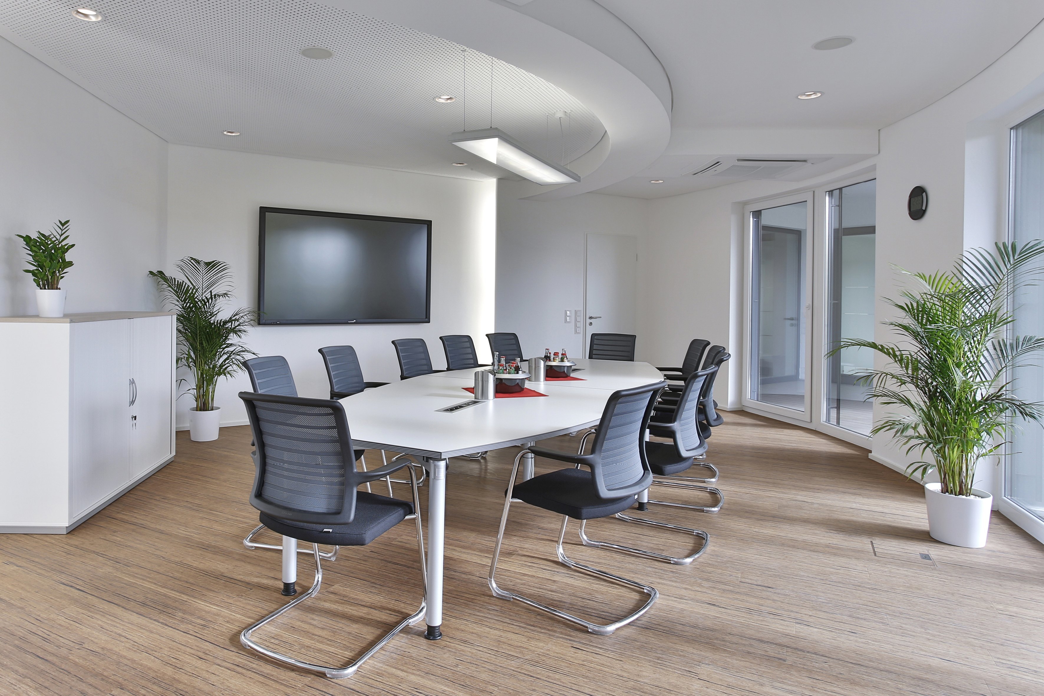 Heller Konferenzraum mit Systo Tec Konferenztisch in Bootsform und modernen Bürostühlen.