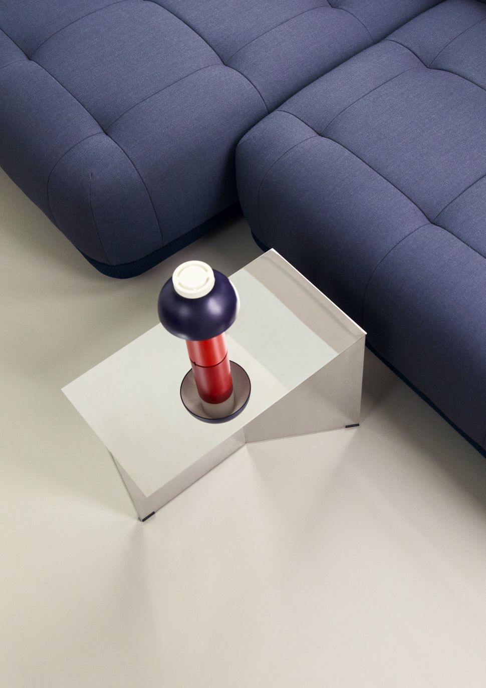 Nahaufnahme des Hay Slit Table Beistelltischs mit Spiegeloberfläche neben einem blauen Sofa.