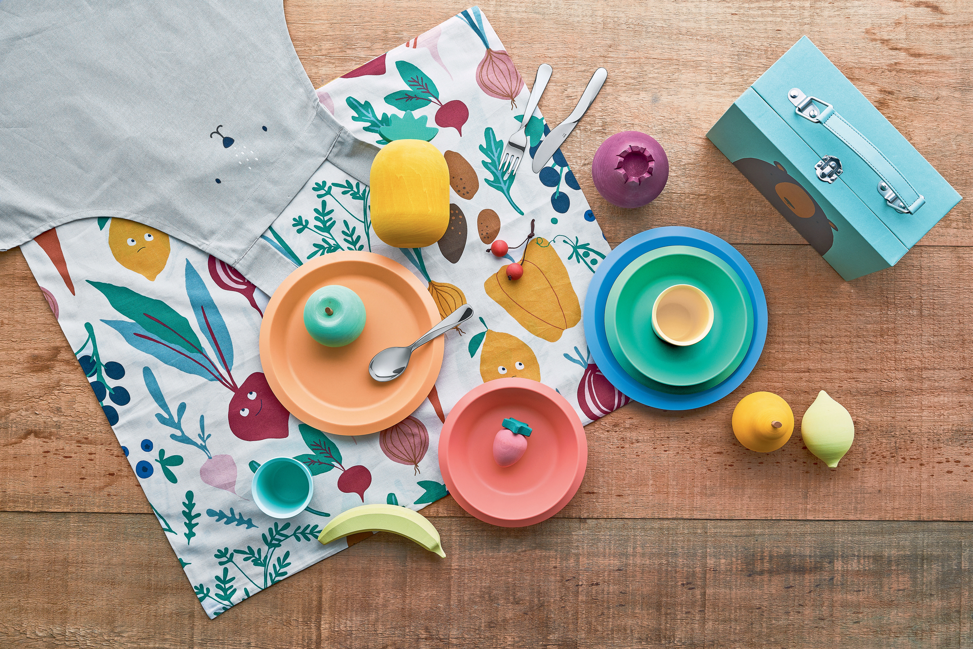 Alessi Kinderbesteck Set: Buntes Kindergeschirr und Besteck aus Edelstahl auf Holztisch.