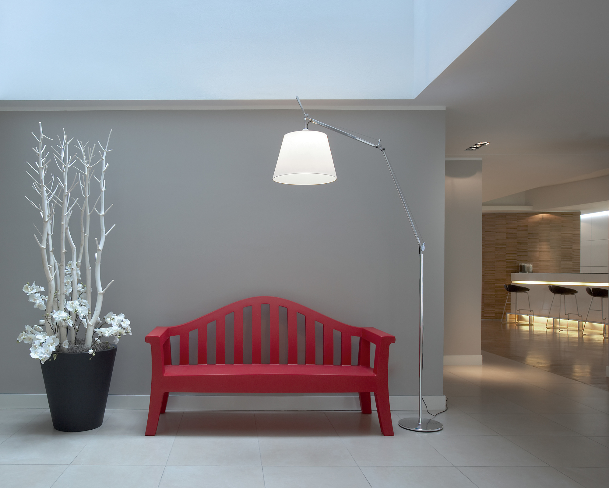 Artemide Tolomeo Mega Stehleuchte mit Schirm neben roter Bank und Dekoration im modernen Wohnraum.