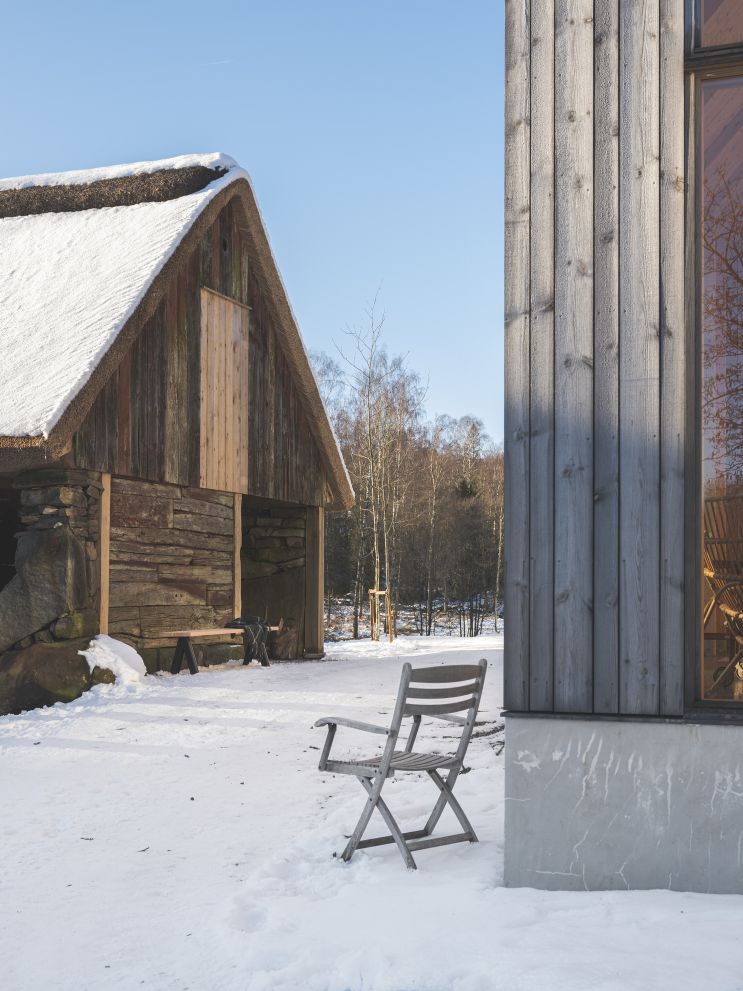 Selandia Armchair Outdoor Sessel von Skagerak by Fritz Hansen im Schnee vor Holzhäusern.