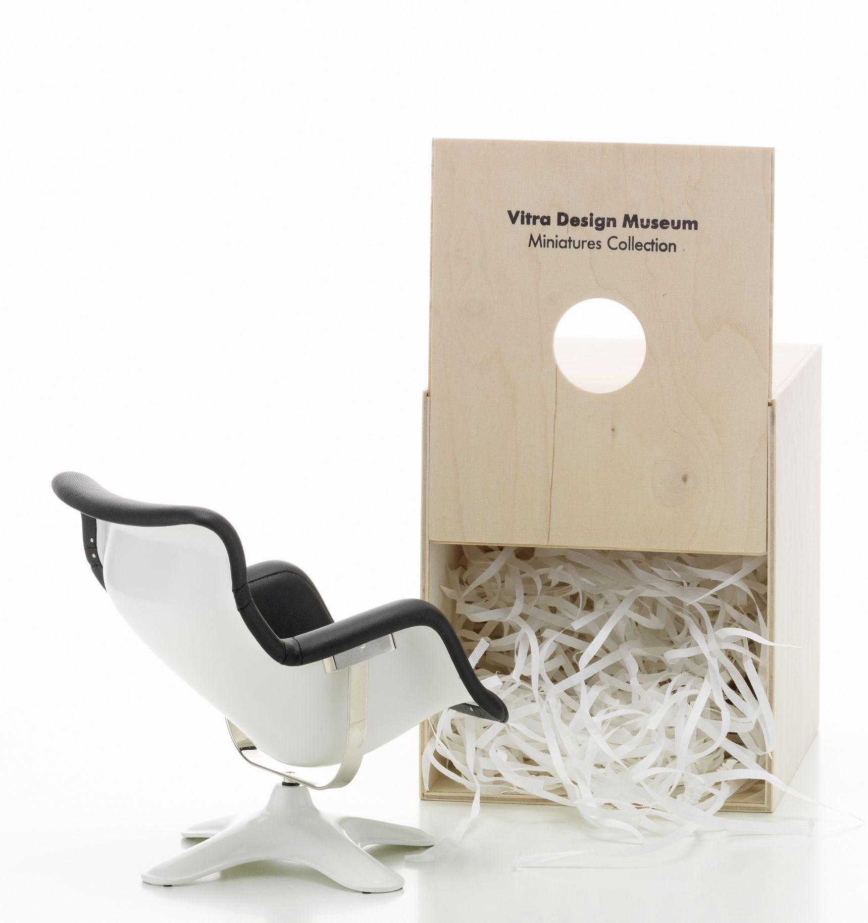 Miniatur Vitra Karuselli Sessel [1964/65] neben einer Holzkiste mit Füllmaterial. Designklassiker.