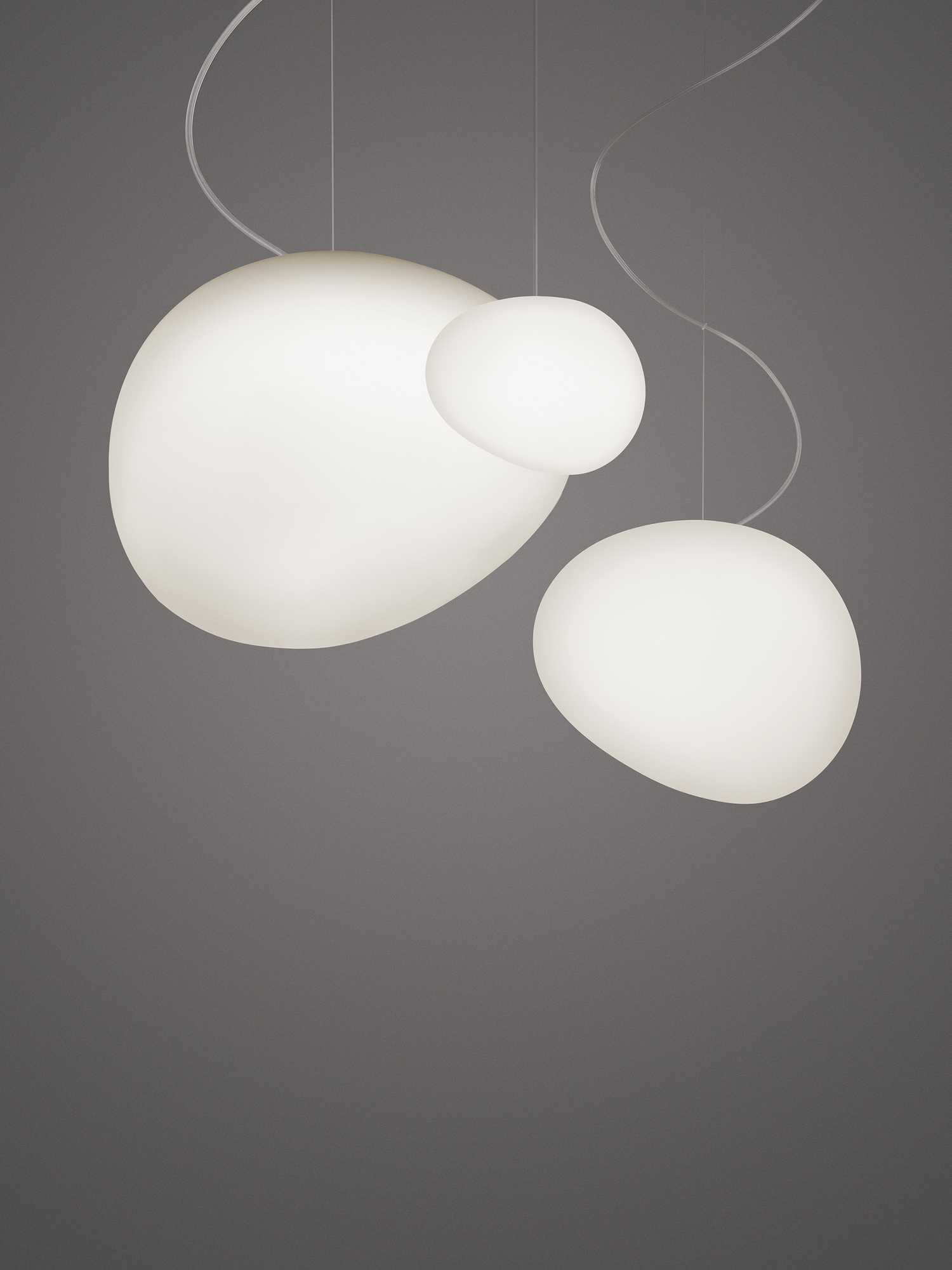 Gregg Pendelleuchte von Foscarini: Drei organisch geformte, weiße Hängelampen mit sanftem Licht.