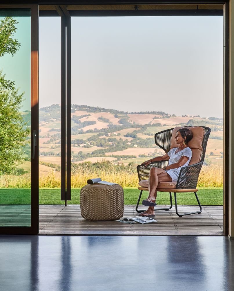 Frau entspannt im Denia Relax Sessel Outdoor mit Sitzpolster auf der Terrasse.