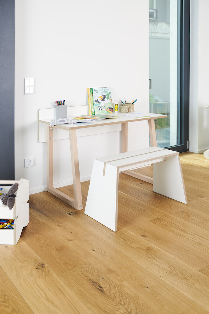 Tojo Kids Werk Schreibtisch mit passendem Hocker, Stiften und Malbuch auf hellem Holzboden.