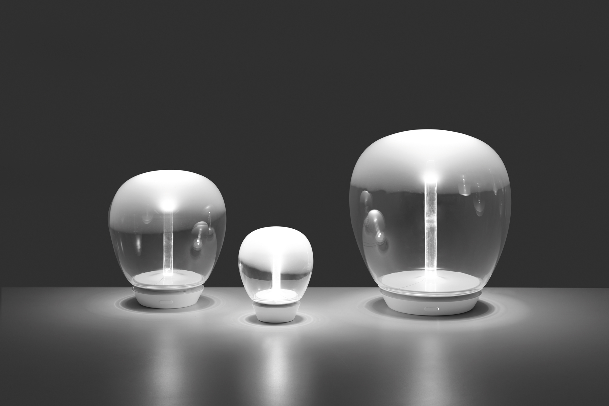 Drei Artemide Empatia Tischleuchten in verschiedenen Größen, modernes Design, stimmungsvolle Beleuchtung.