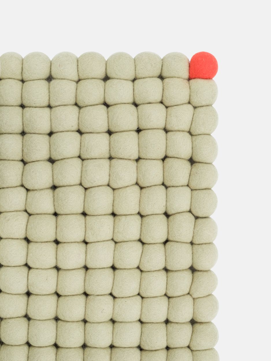 Detailaufnahme des Big One Filzteppichs in Grünbeige, gefertigt aus vielen kleinen Filzkugeln.