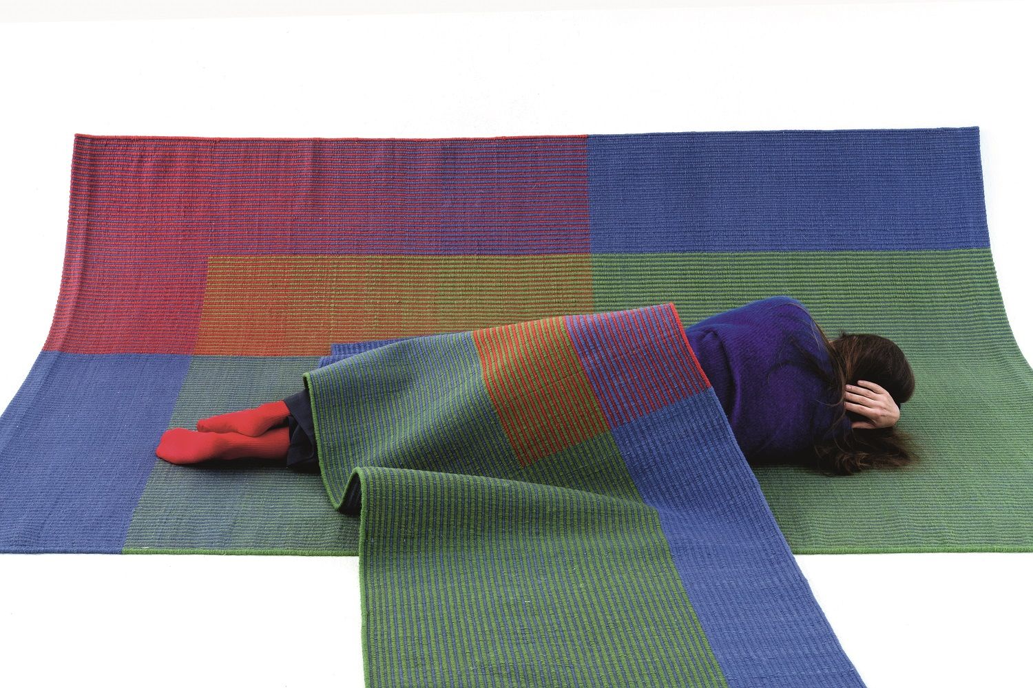 Frau liegt auf dem farbenfrohen Haze Runner Teppich von Nanimarquina, Studio Ambiente.