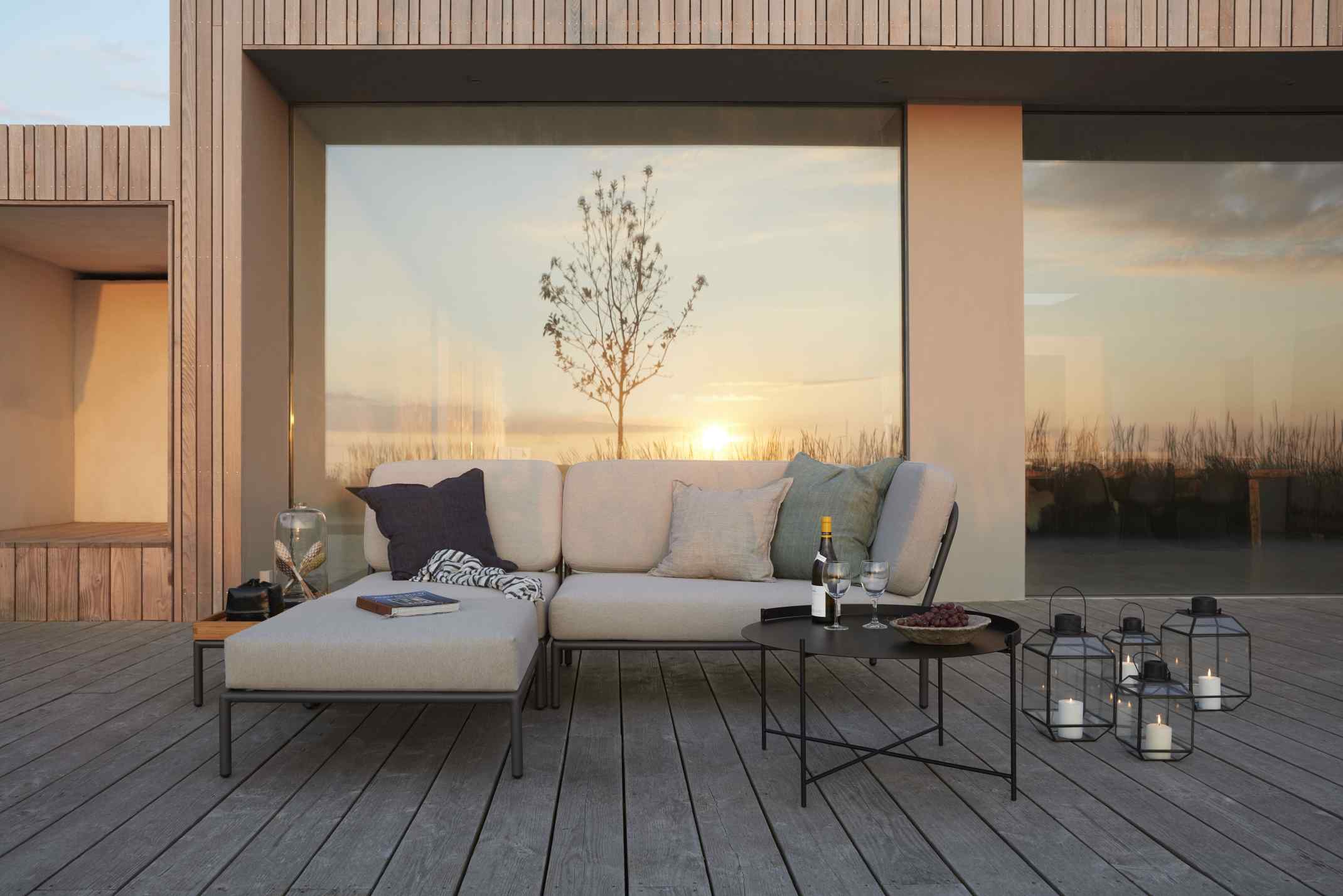 Houe Level Beistelltisch Outdoor neben Lounge-Möbeln auf Holzterrasse mit Laternen und Abendsonne.