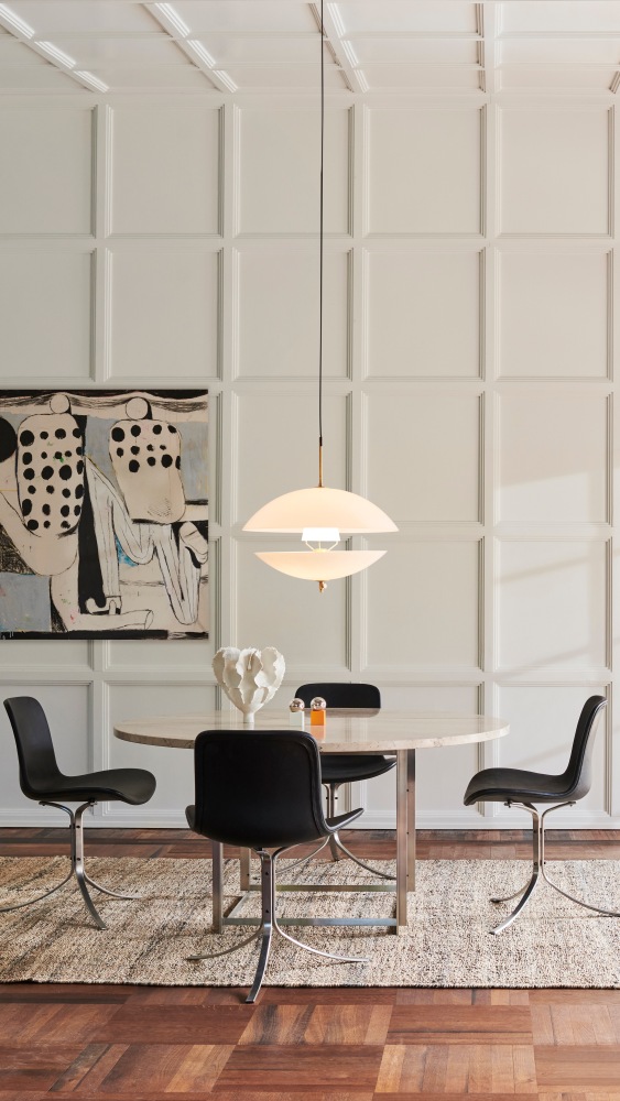 Clam Pendelleuchte von Fritz Hansen über Esstisch mit Stühlen und Kunstwerk im Hintergrund.