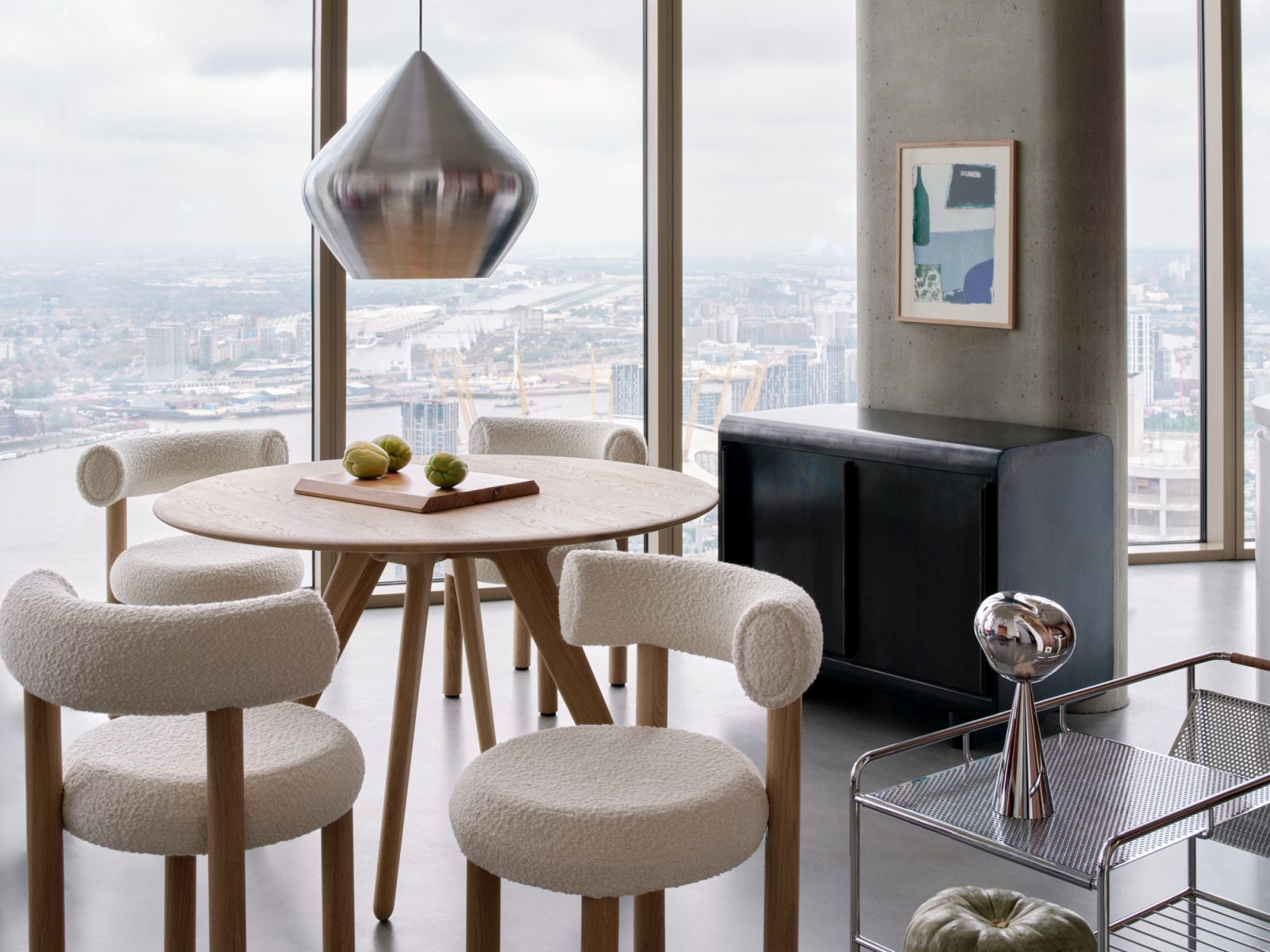 Moderne Esszimmerszene mit Tom Dixon Unbeaten Stout Pendelleuchte über einem Holztisch mit Stühlen.