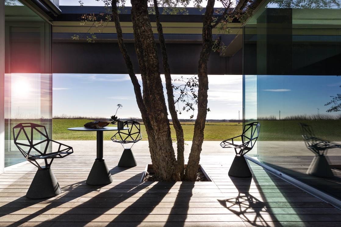 Table One Bistrot Tisch von Magis mit Stühlen im Außenbereich auf einer Holzterrasse.
