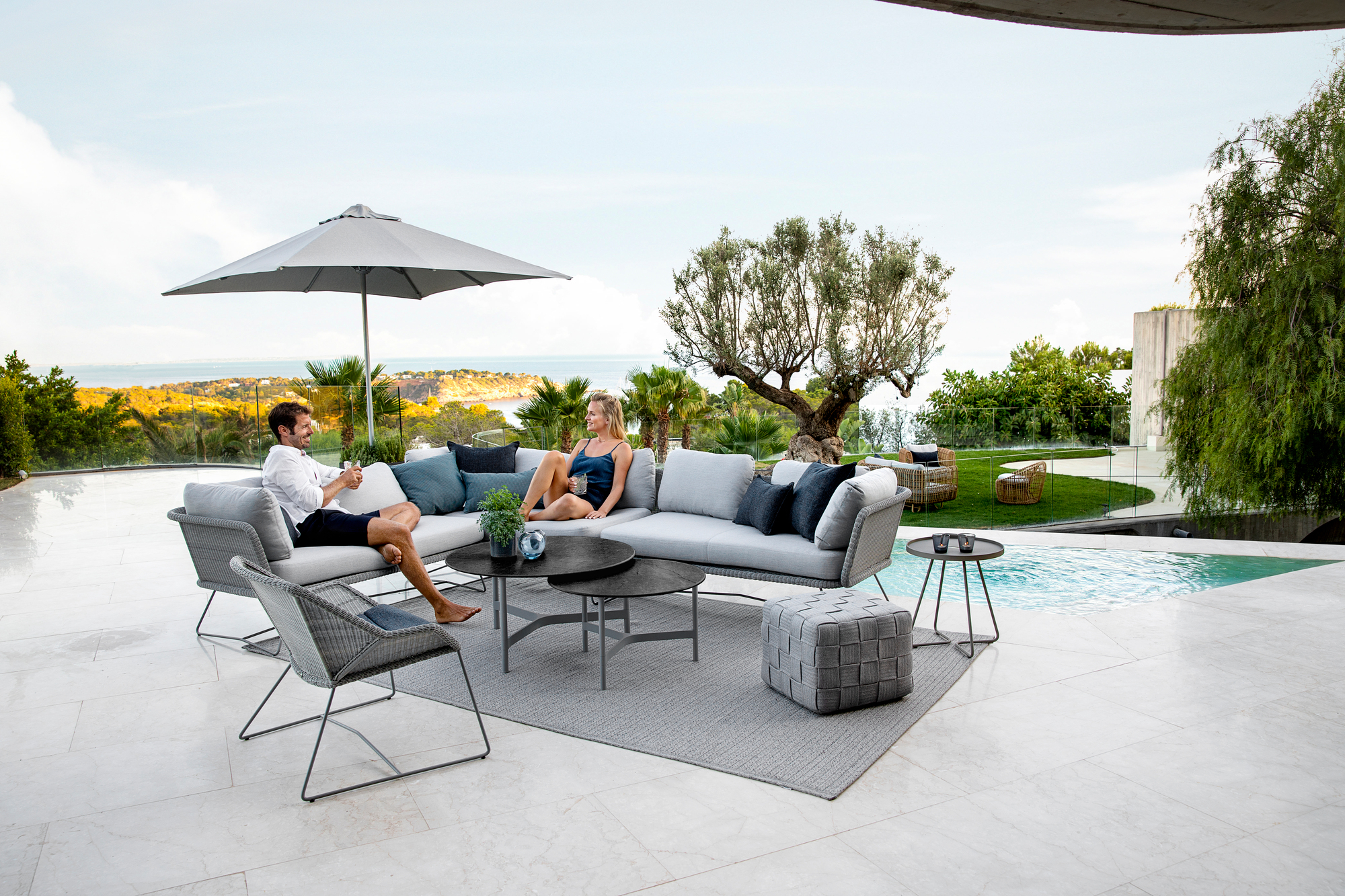 Horizon Outdoor Modulsofa von Cane-Line: Graues 2-Sitzer Sofa mit Kissen auf einer Terrasse.