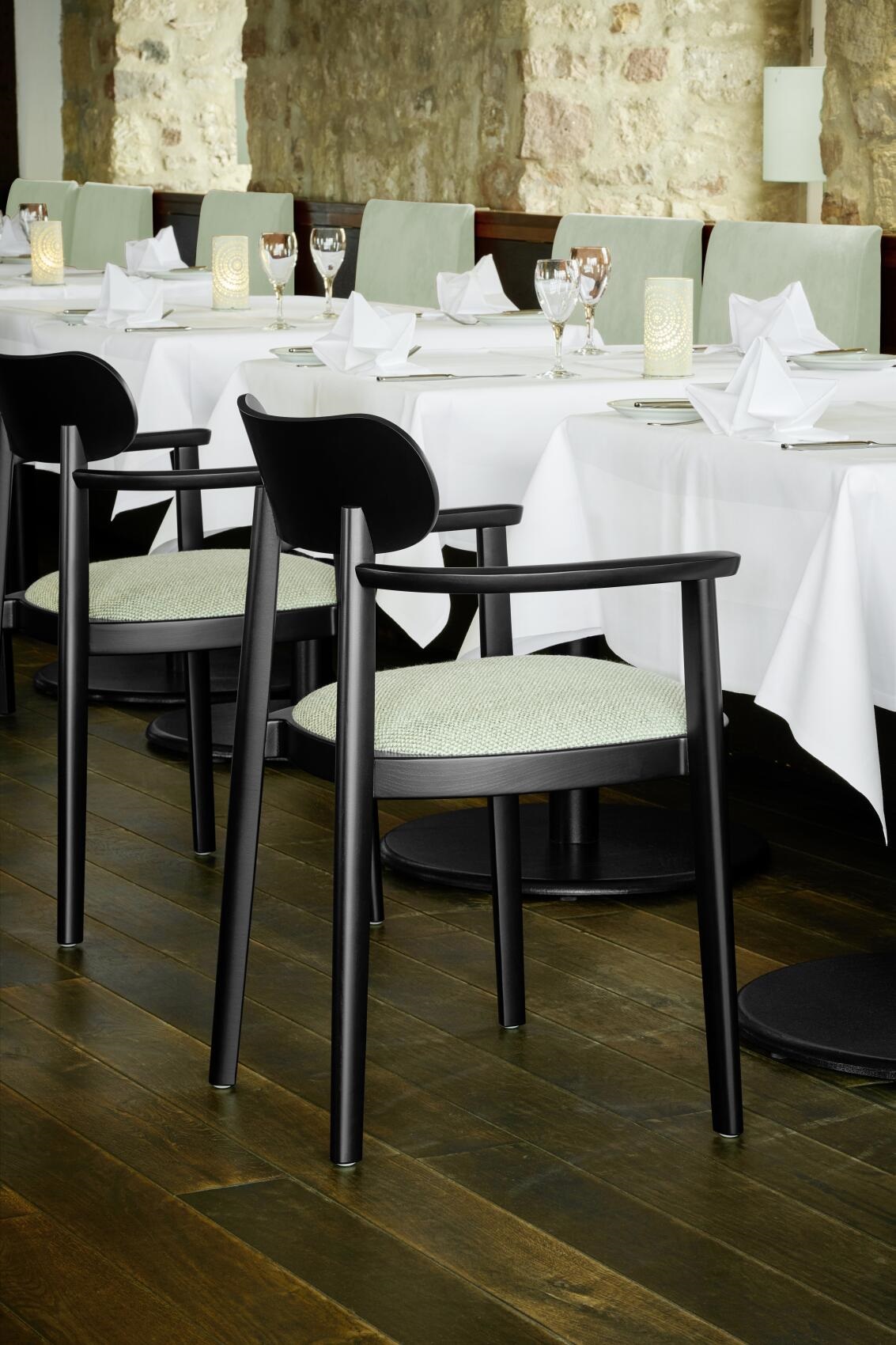 Schwarzer 118 SPFV Holzstuhl mit Armlehnen von Thonet, hellgrüner Sitzbezug, im Restaurant.