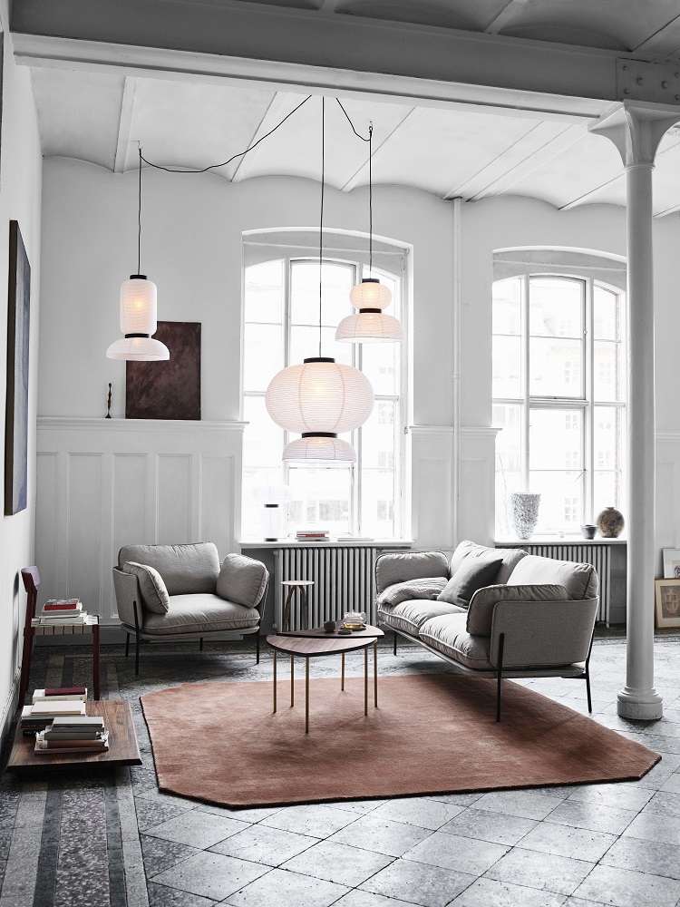 Wohnzimmer mit AndTradition Pinwheel HM7 Table Beistelltisch, Sofa, Sessel und Teppich in modernem Design.