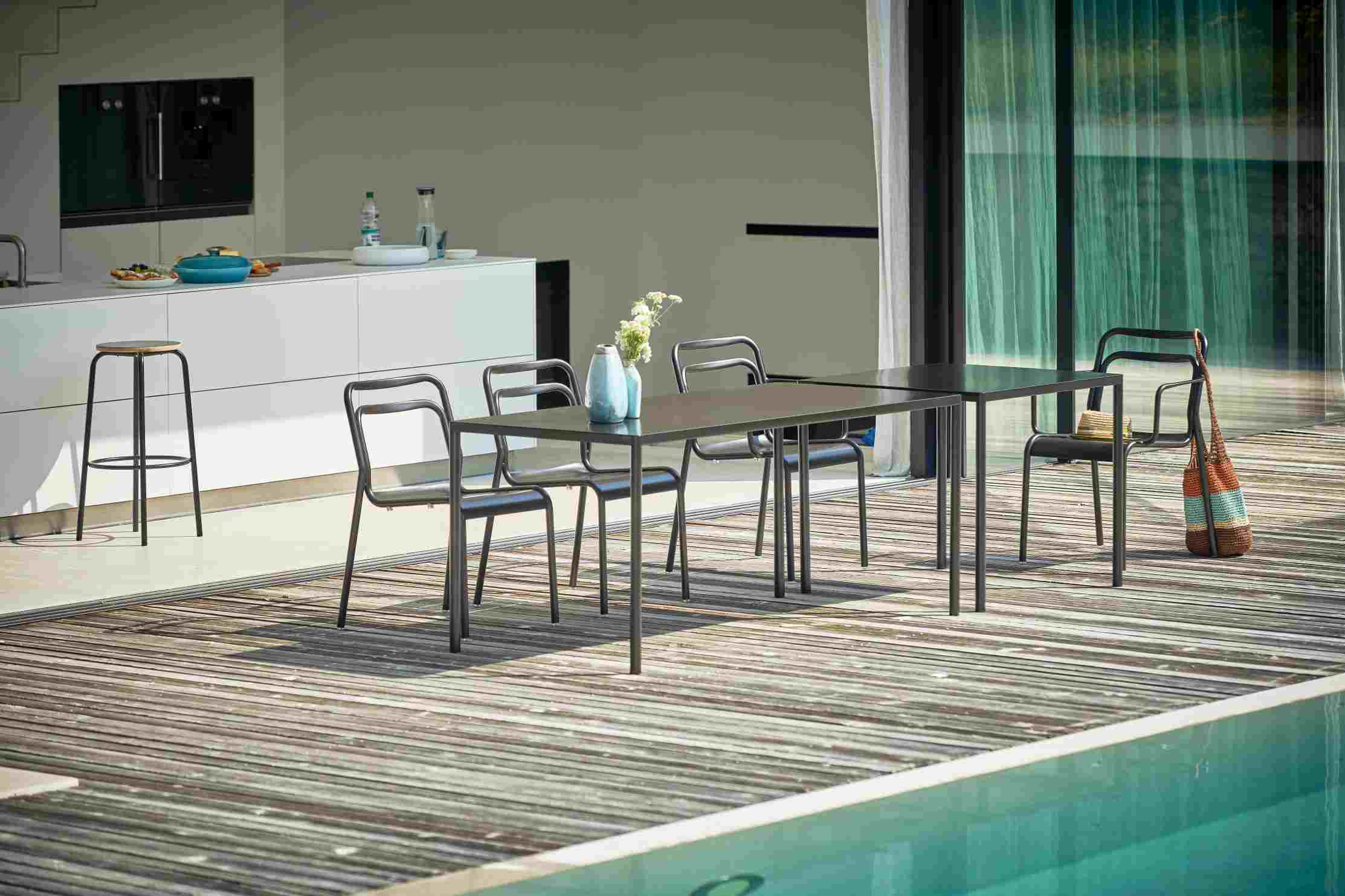 Schwarzer Jan Kurtz Live Tisch mit Stühlen im Außenbereich neben einem Pool. Outdoor Möbel.