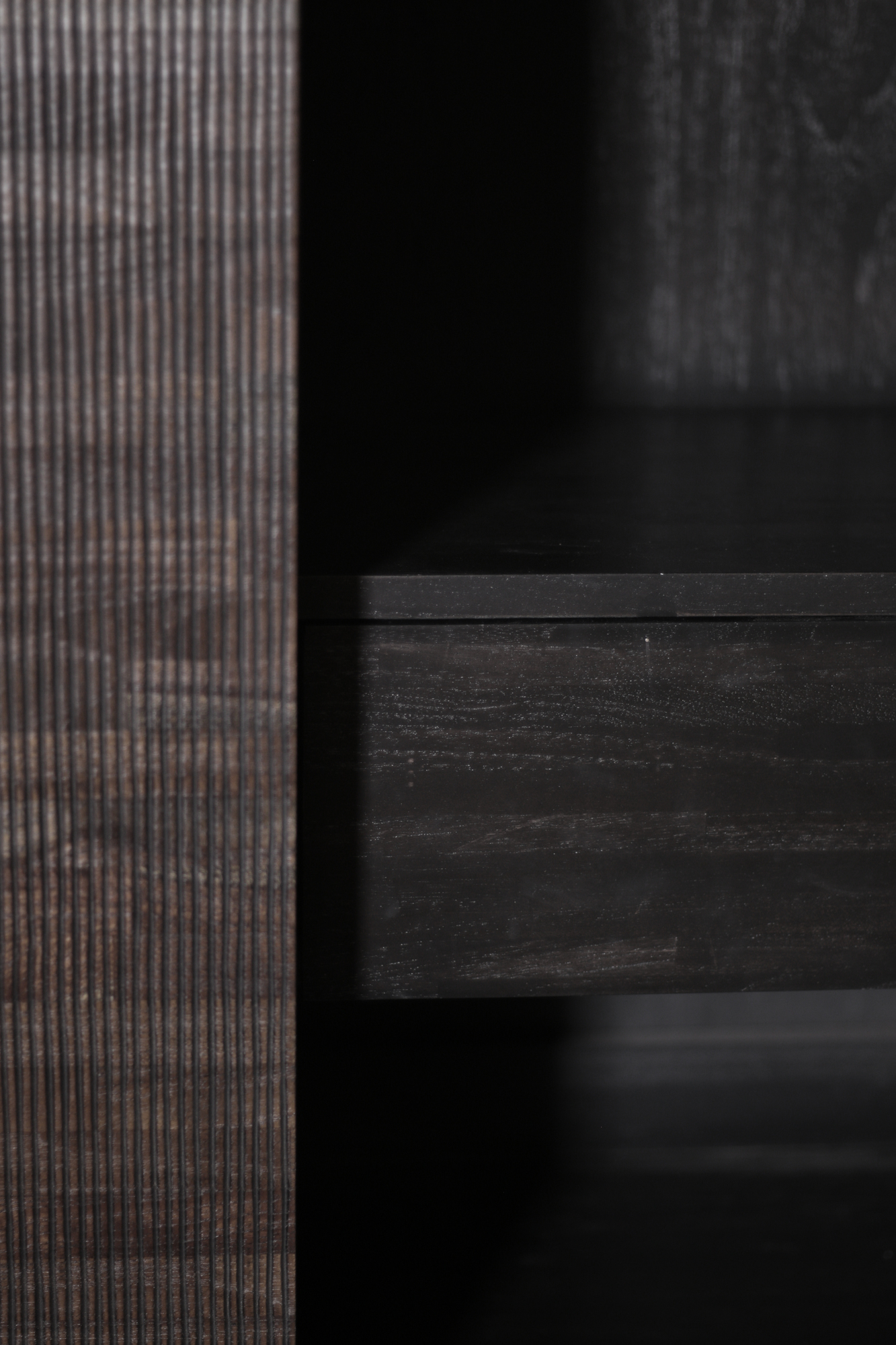 Detailaufnahme des Ethnicraft Teak Grooves Schrankes: Schublade und geriffelte Teakholz-Oberfläche in dunkler Ausführung.