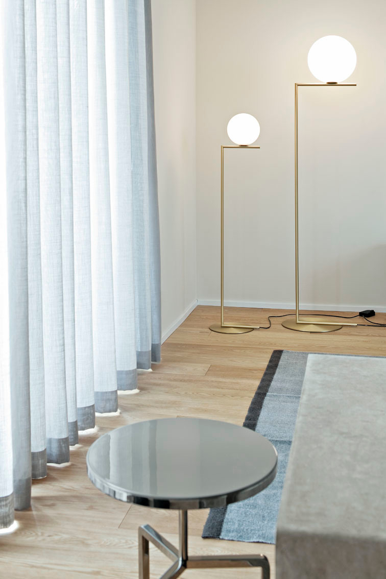Zwei goldene IC Lights Stehlampen von Flos mit runden, weißen Lampenschirmen im modernen Wohnzimmer.